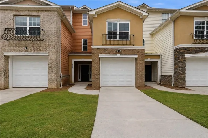 Townhome exterior featuring varied siding materials, attached garages, and individual front entrances