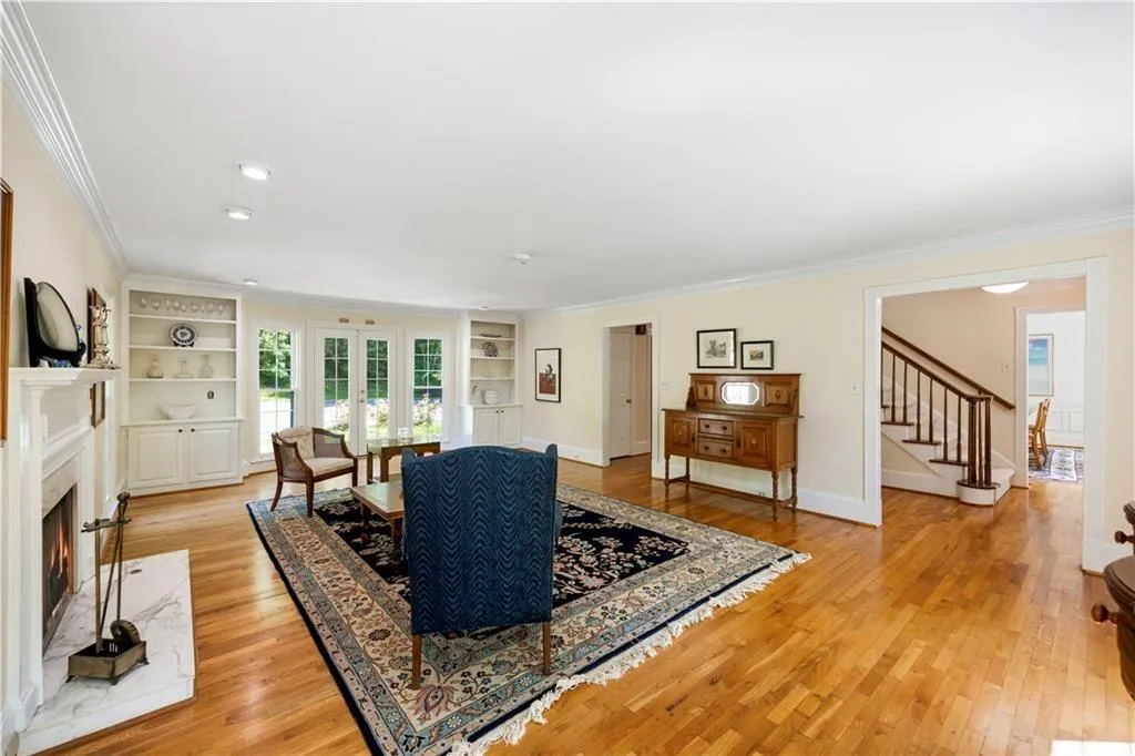 Living area with light wood finished floors, built in features, stairs, and ornamental molding