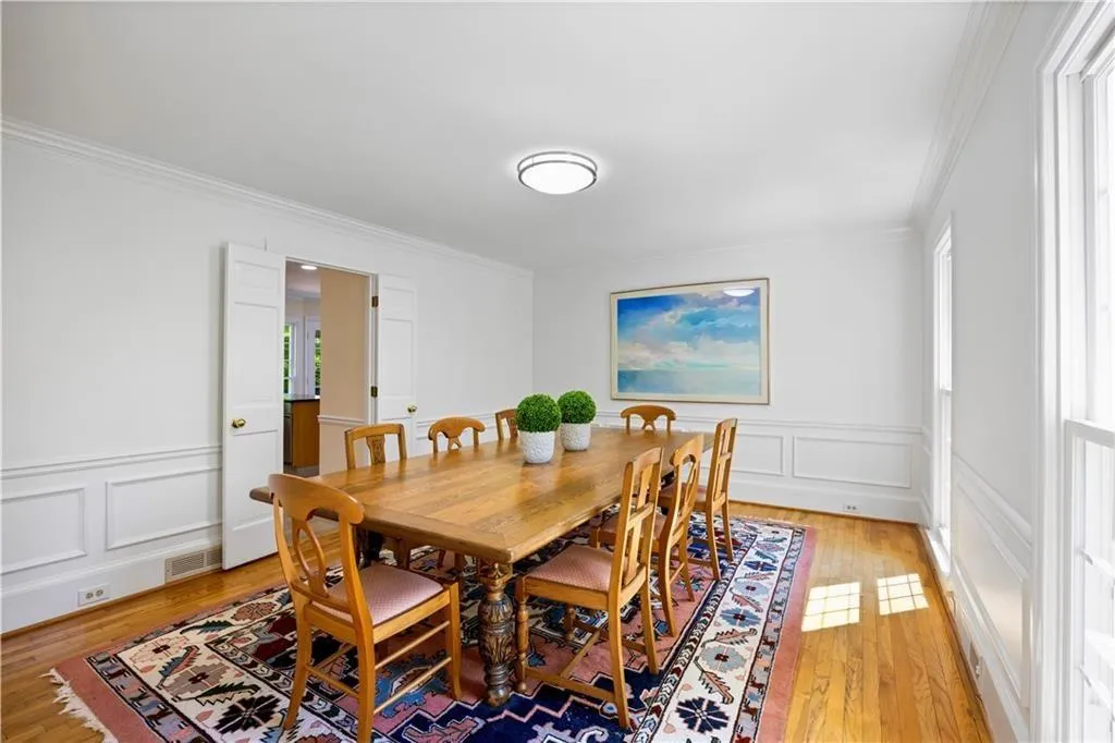 Dining space with a decorative wall, ornamental molding, visible vents, and light wood finished floors