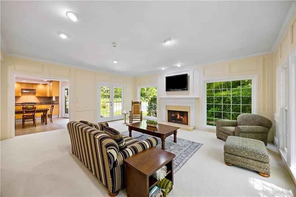 Living area featuring a decorative wall, a warm lit fireplace, french doors, and recessed lighting