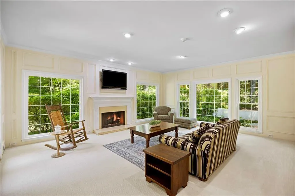 Living room featuring a decorative wall, a warm lit fireplace, and light carpet