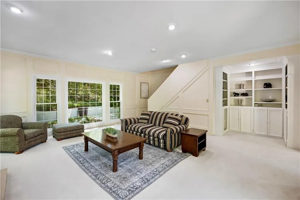 Living room with a decorative wall, crown molding, and light colored carpet