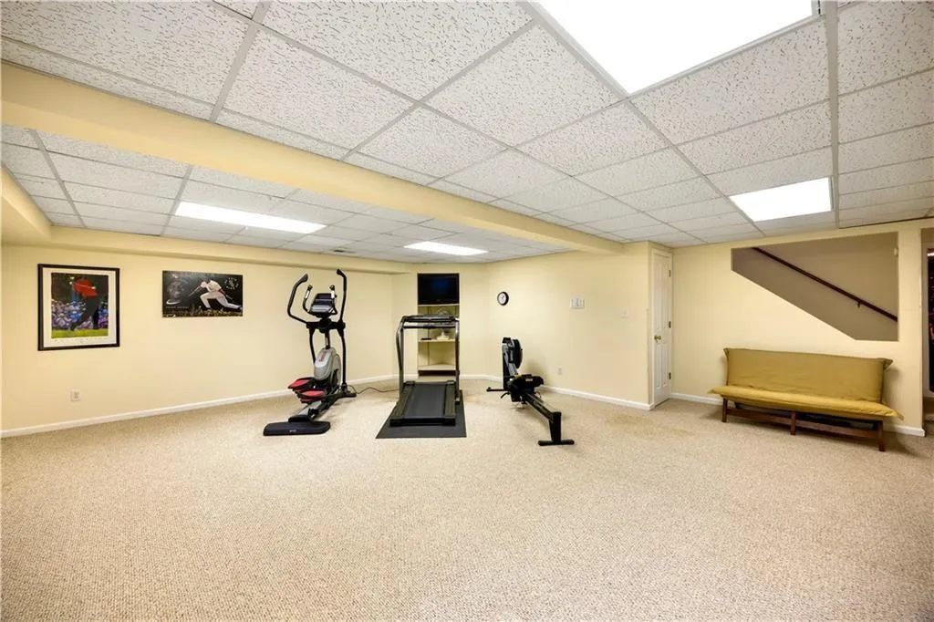 Exercise area featuring a paneled ceiling, baseboards, and carpet flooring