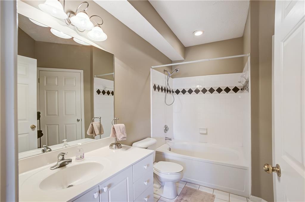 Full bathroom with toilet, tiled shower / bath combo, a notable chandelier, tile floors, and vanity