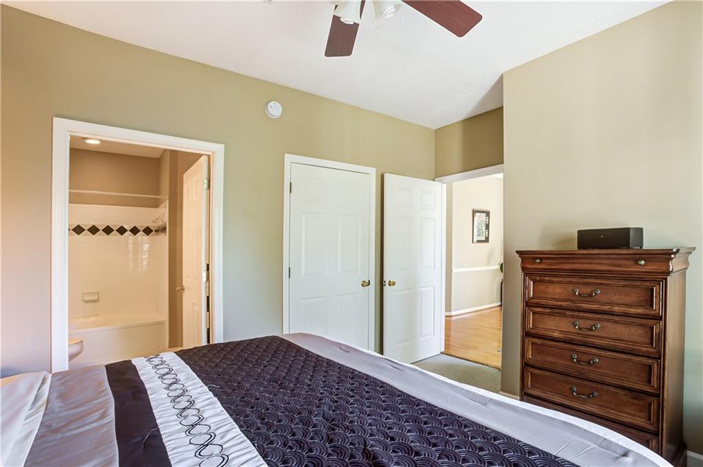 Bedroom with ceiling fan, connected bathroom, wood-type flooring, and a closet