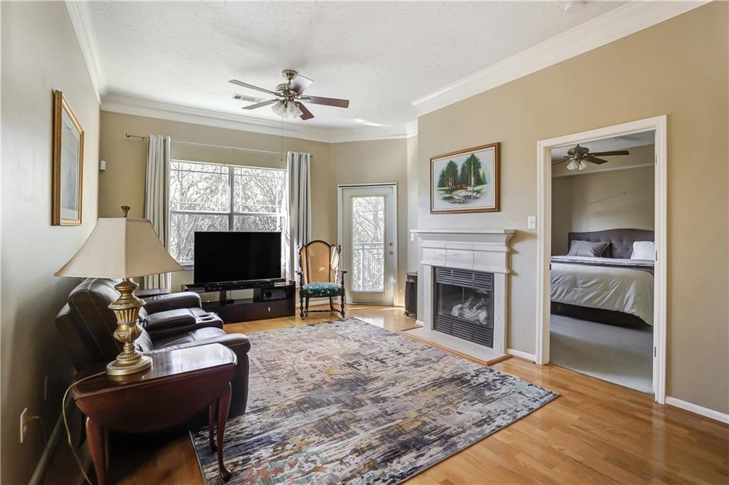 Living room featuring ceiling fan, crown molding, and light hardwood / wood-style floors