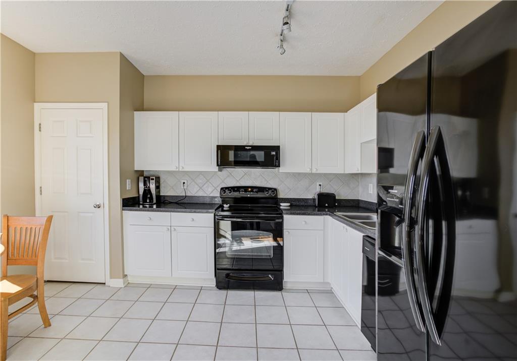 Kitchen featuring black appliances, white cabinets, and tasteful backsplash