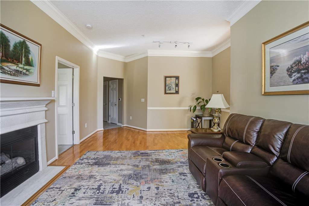 Living room with ornamental molding, track lighting, and light hardwood / wood-style floors