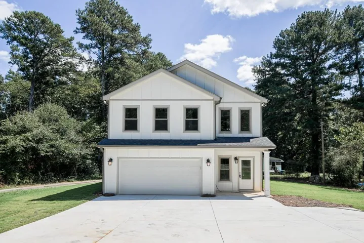 Two-story exterior with white siding, an attached two-car garage, a covered entry with a column, and a concrete driveway
