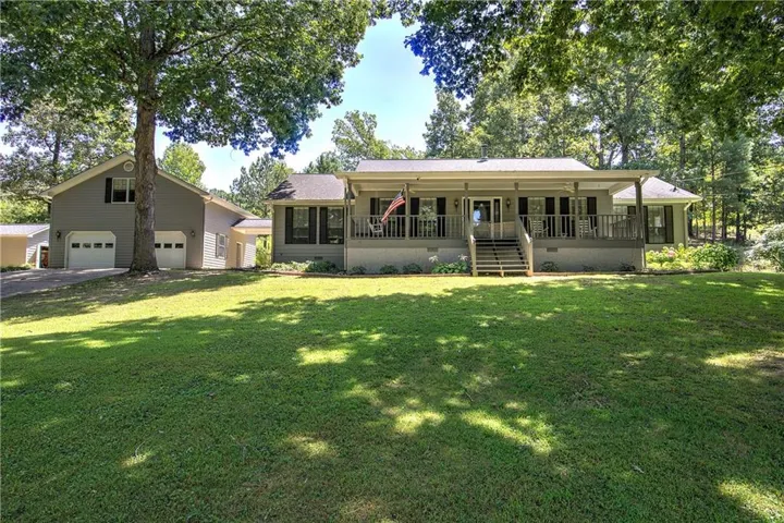 Expansive front lawn with mature trees and a long covered porch