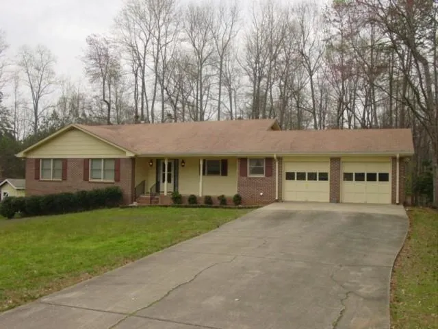 Ranch-style residence featuring a brick facade, light yellow siding, and a covered front porch