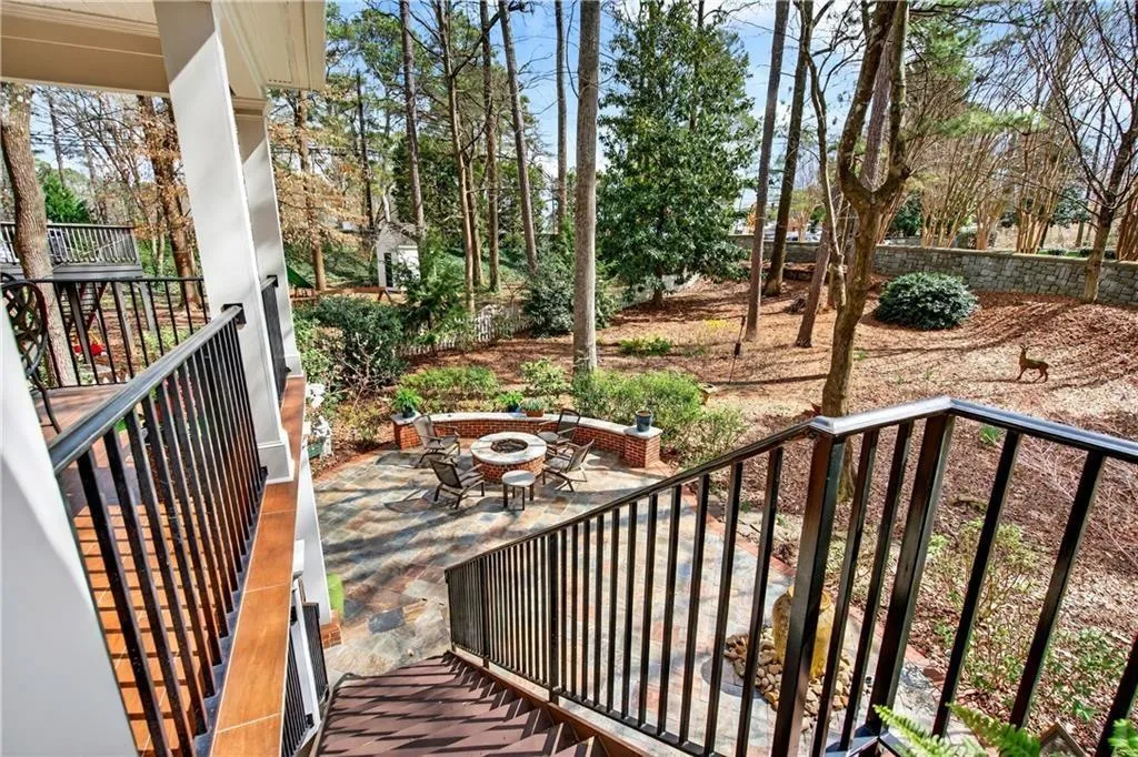 Stairs leading down to stone patio featuring gas fire pit, water feature, and outdoor kitchen.