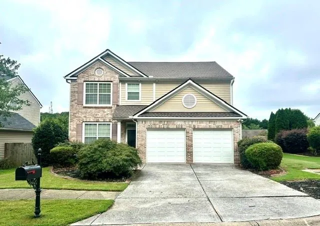 Two-story residence featuring brick and siding exterior, a double garage, and a concrete driveway