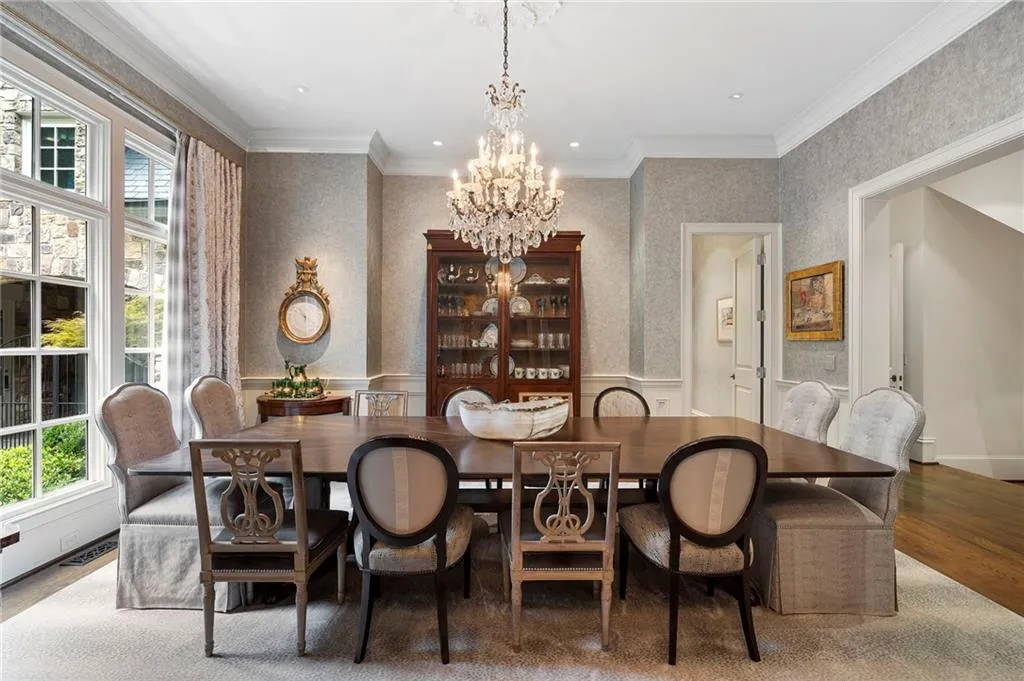 Formal dining room featuring a substantial wood table and varied seating, illuminated by a crystal chandelier