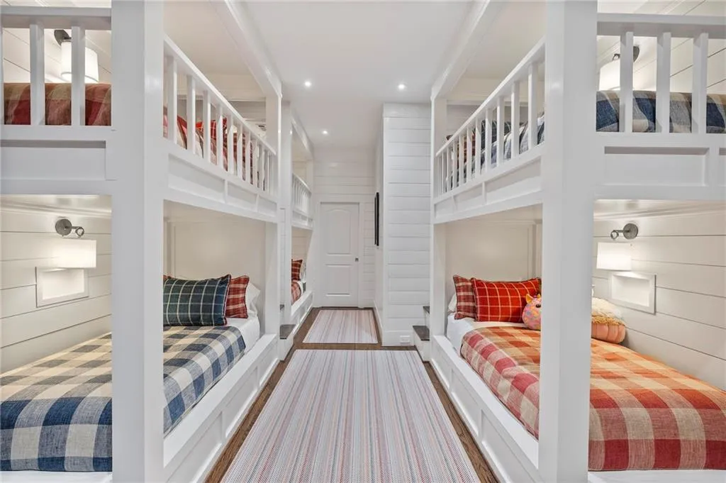 Built-in bunk beds with integrated lighting, planked wall finishes, wood-finish flooring, and a white paneled door