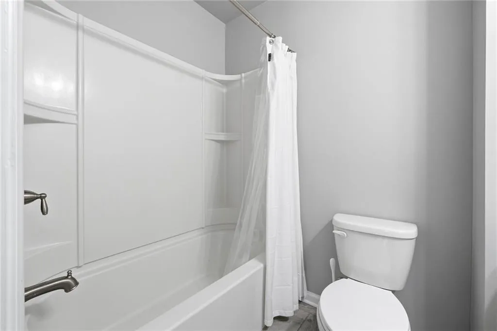 Full bath featuring toilet and shower / tub combo with curtain