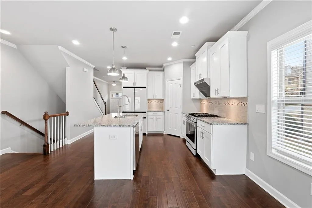 Kitchen featuring white cabinetry, tasteful backsplash, dark wood finished floors, stainless steel range with gas cooktop, and light stone counters