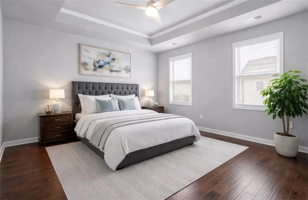 Bedroom with a raised ceiling, dark wood-type flooring, ceiling fan, and crown molding