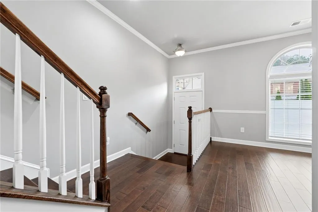 Entrance foyer featuring ornamental molding and dark wood-style flooring