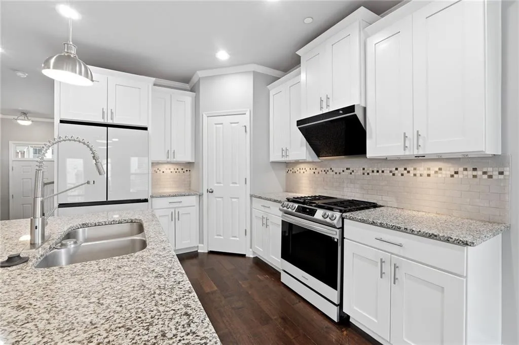 Kitchen with white cabinets, gas range, ornamental molding, freestanding refrigerator, and dark wood-type flooring