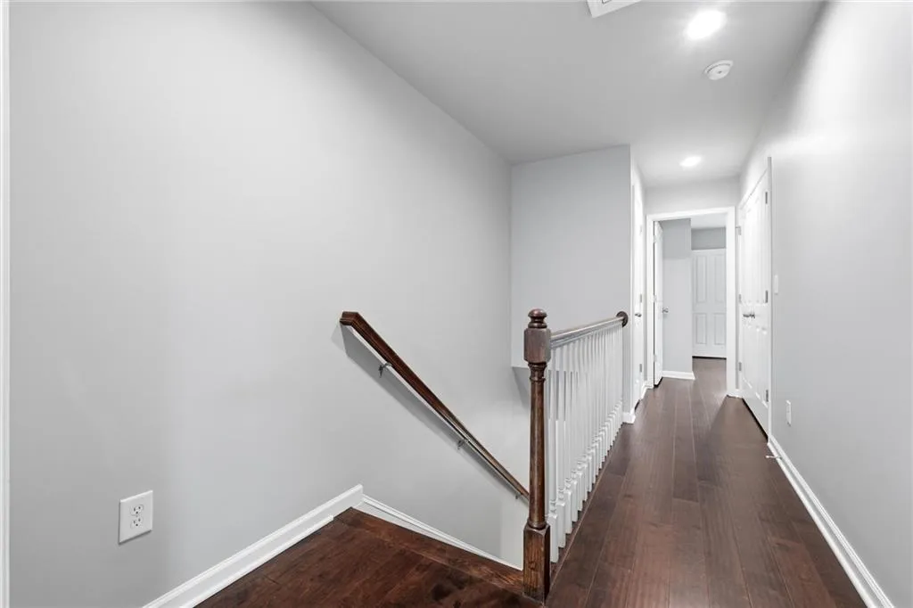Hall with an upstairs landing, dark wood finished floors, and recessed lighting