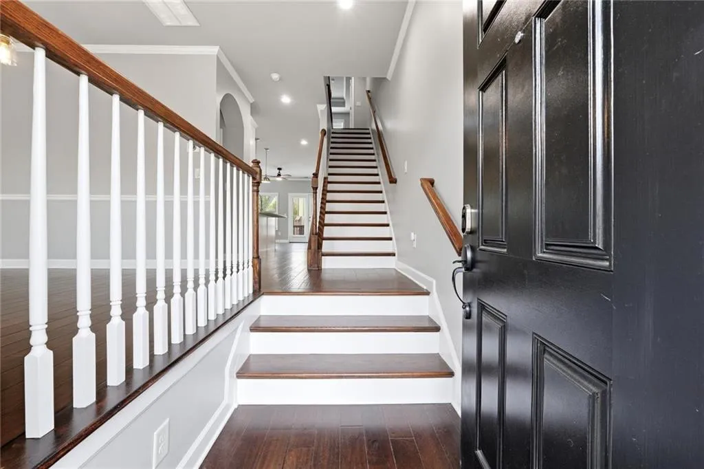Stairway featuring hardwood / wood-style flooring, arched walkways, ornamental molding, and recessed lighting