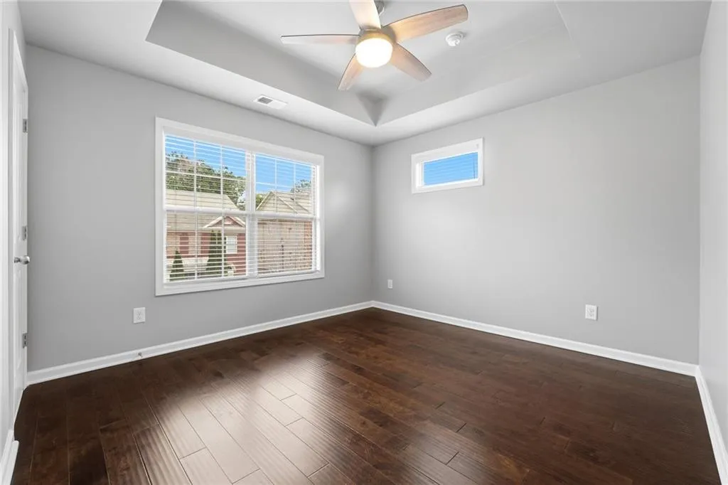 Spare room featuring a raised ceiling, a ceiling fan, and dark wood-type flooring