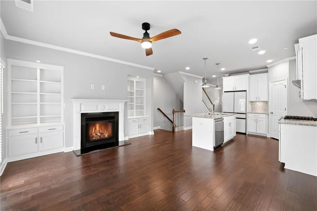 Kitchen with white cabinetry, crown molding, built in shelves, open floor plan, and light stone counters