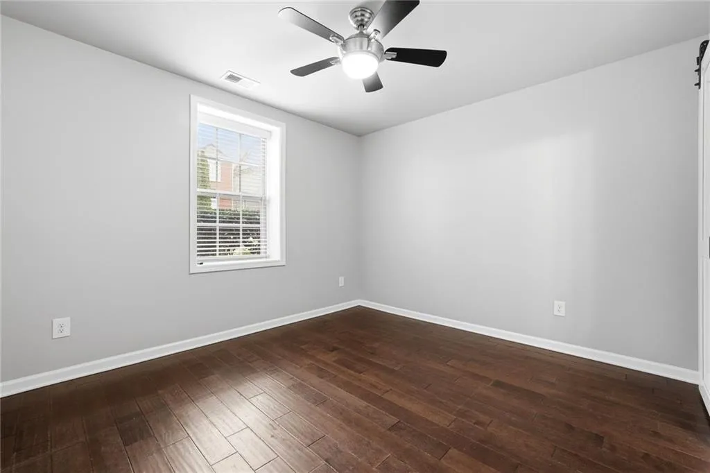 Unfurnished room featuring ceiling fan and dark wood-style floors