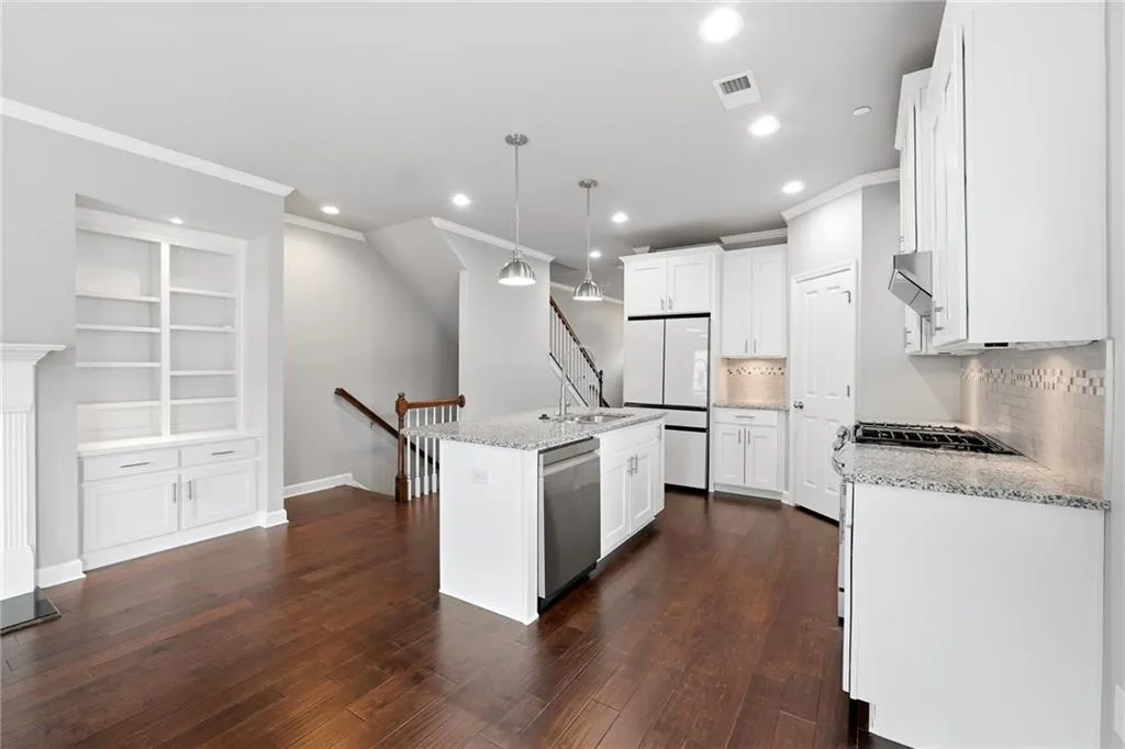 Kitchen with backsplash, white cabinetry, ornamental molding, dark wood-style floors, and pendant lighting