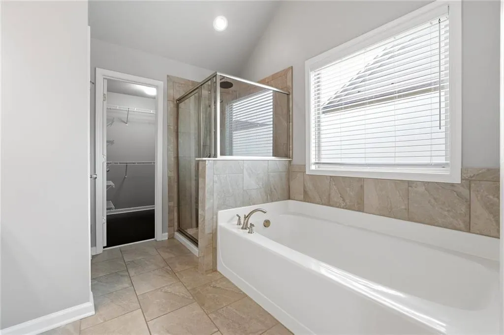 Bathroom with a garden tub, a shower stall, lofted ceiling, and a walk in closet