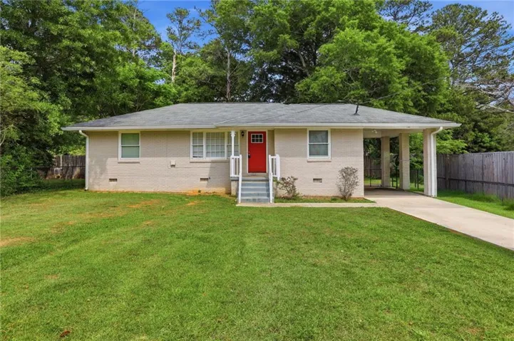 Brick exterior with a vibrant red entry door, white window trim, and a covered carport
