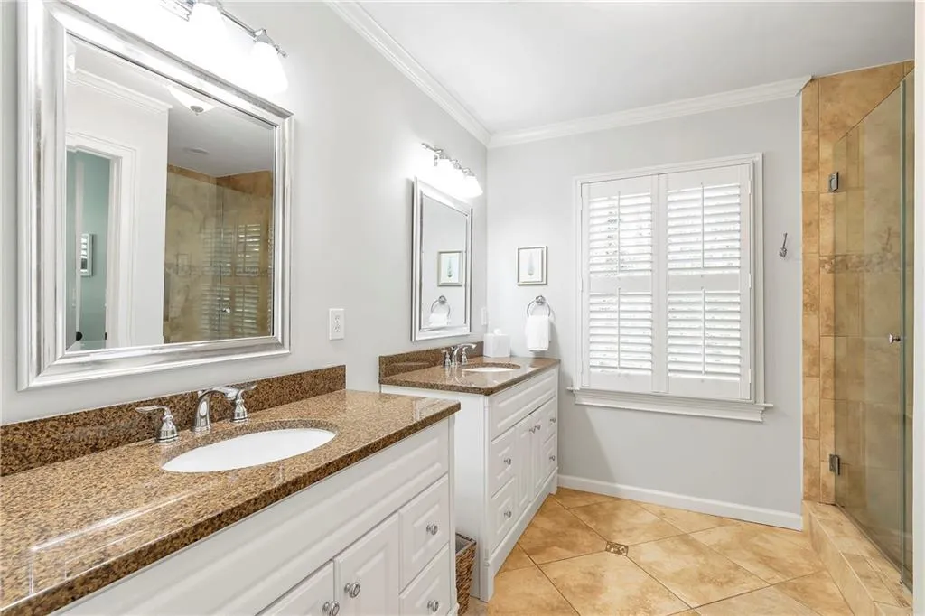 Bathroom featuring a shower with door, dual bowl vanity, tile flooring, and crown molding