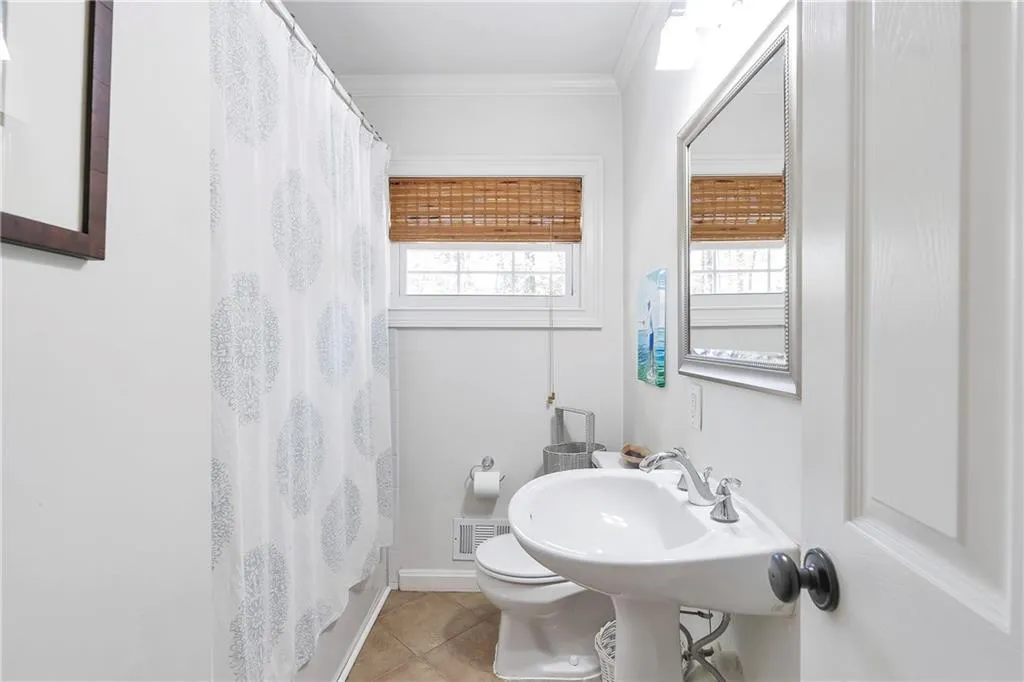 Bathroom featuring toilet, tile floors, and crown molding