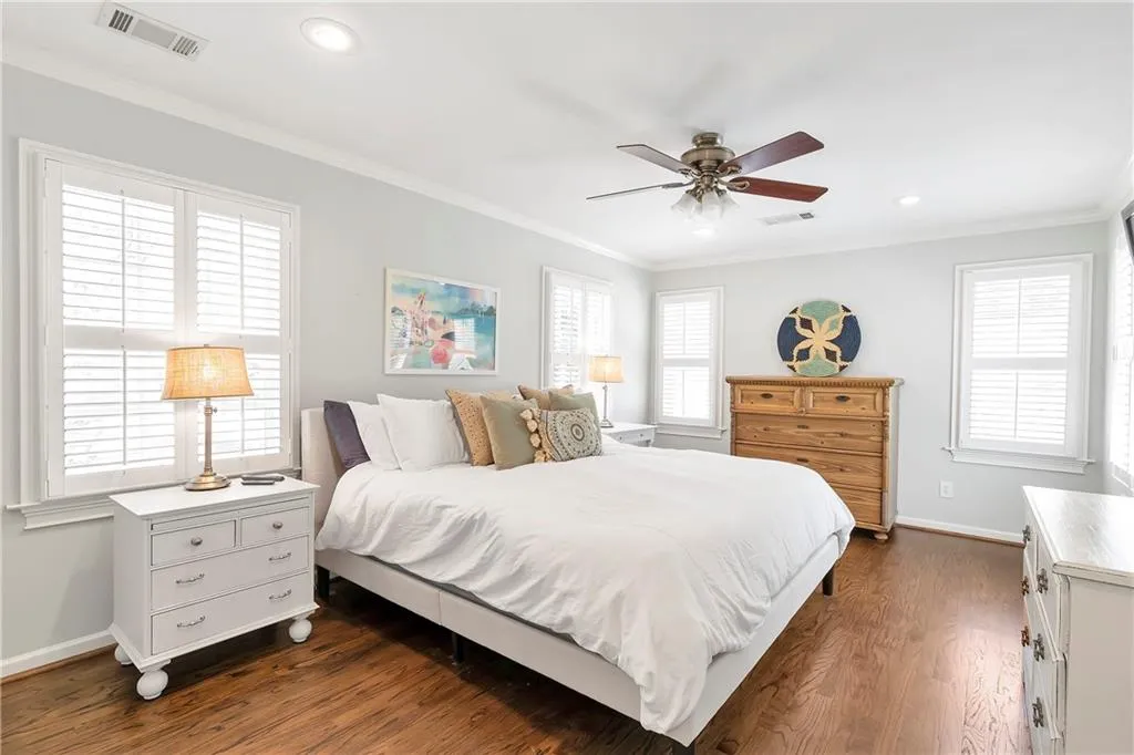 Bedroom featuring crown molding, dark hardwood / wood-style floors, ceiling fan, and multiple windows