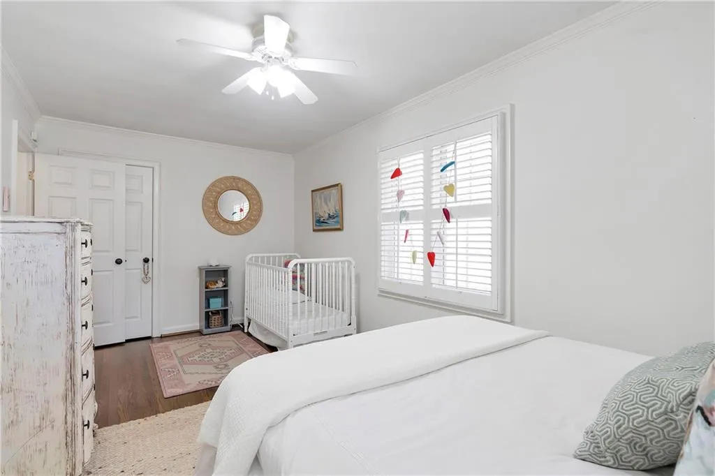 Bedroom featuring dark hardwood / wood-style floors, ceiling fan, and ornamental molding