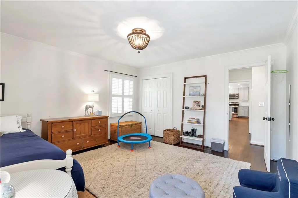 Bedroom featuring a closet, dark wood-type flooring, and ornamental molding