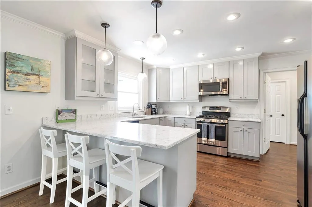 Kitchen with kitchen peninsula, pendant lighting, dark hardwood / wood-style flooring, appliances with stainless steel finishes, and a breakfast bar area