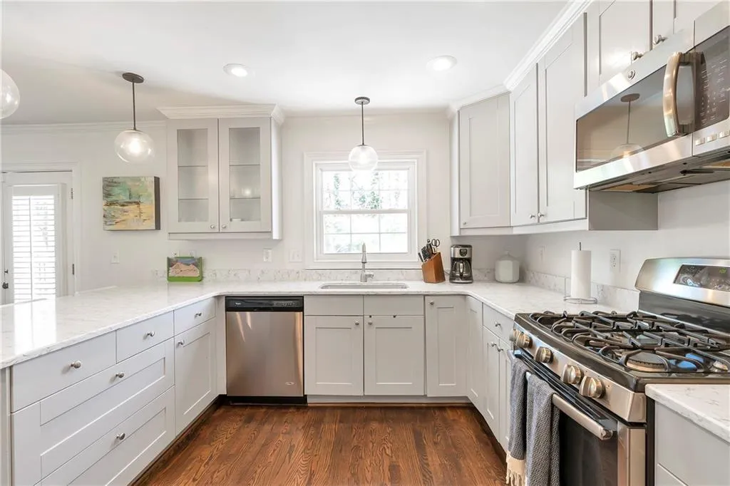 Kitchen featuring white cabinetry, sink, stainless steel appliances, light stone counters, and dark hardwood / wood-style flooring