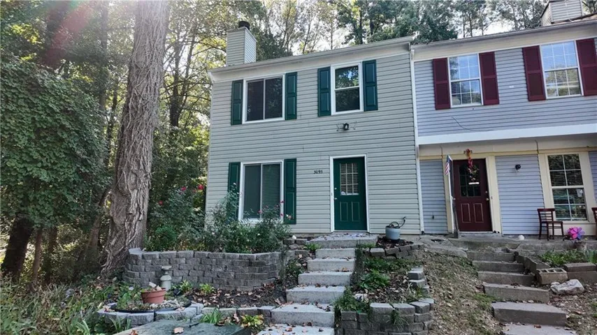 Split-level townhome featuring light-colored siding and a dark green front door