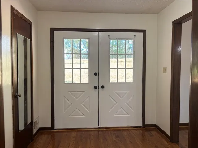 Double entry doors with divided light windows, dark wood-finish trim, and wood-finish flooring