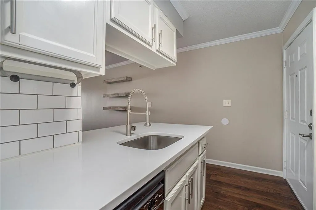 Kitchen featuring crown molding, a textured ceiling, dark hardwood / wood-style flooring, white cabinets, and sink