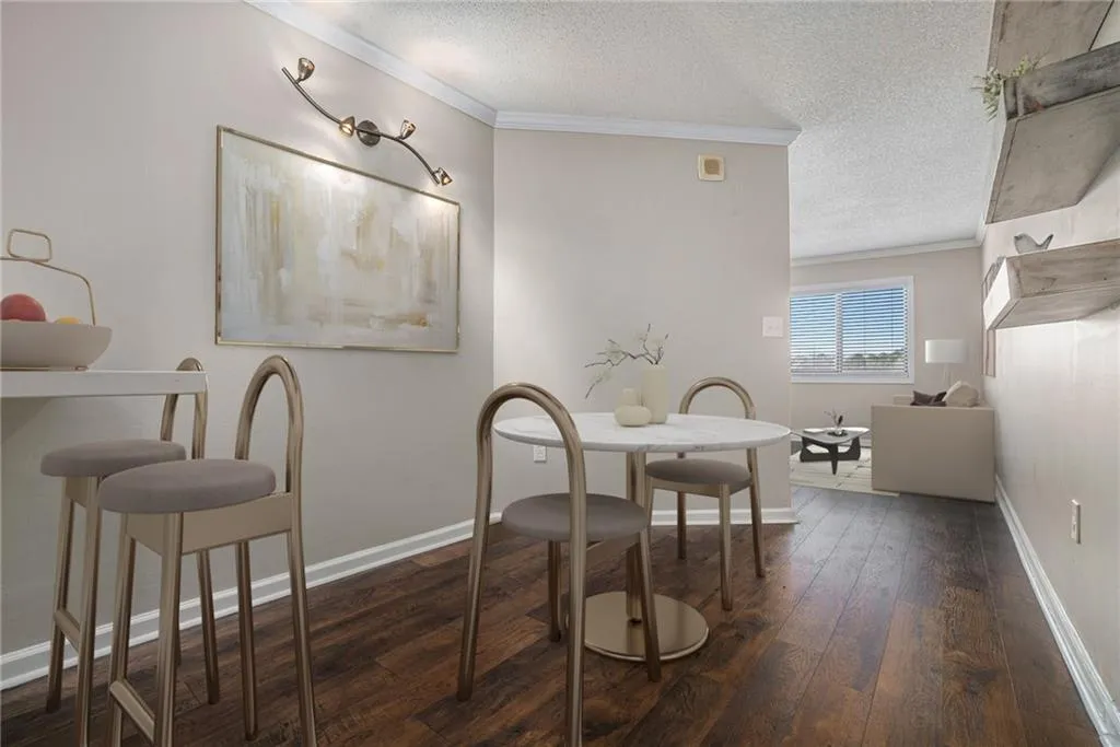 Dining area with dark wood-type flooring, ornamental molding, and a textured ceiling
