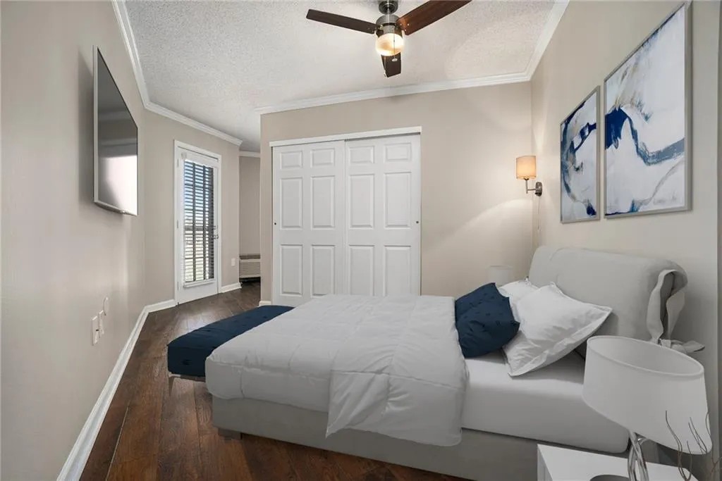 Bedroom featuring crown molding, a textured ceiling, ceiling fan, a closet, and dark wood-type flooring