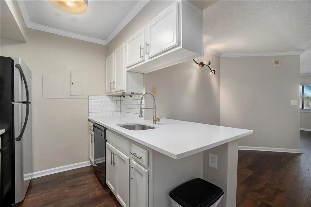 Kitchen with white cabinets, sink, dark hardwood / wood-style floors, and stainless steel fridge