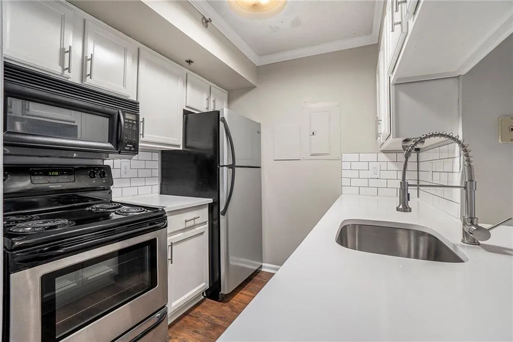 Kitchen featuring dark hardwood / wood-style floors, backsplash, sink, white cabinets, and appliances with stainless steel finishes