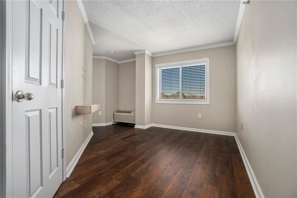 Spare room featuring crown molding, a textured ceiling, and dark wood-type flooring