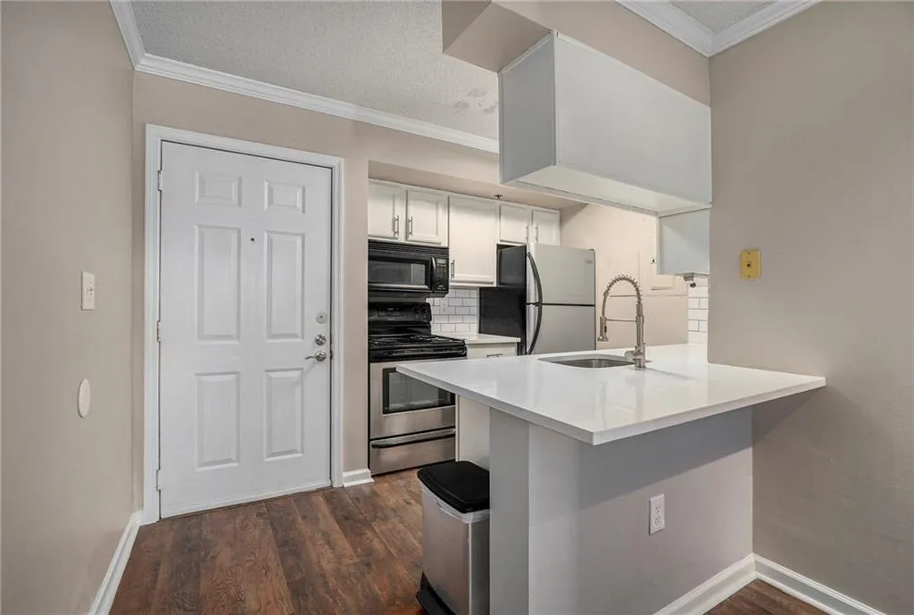 Kitchen featuring appliances with stainless steel finishes, ornamental molding, and dark hardwood / wood-style floors