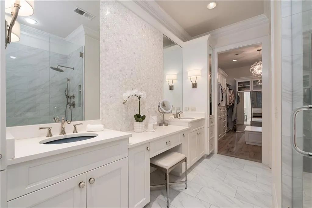 Spa-like Bathroom with dual vanity, a notable chandelier, tile /marble floors, walk in shower, and ornamental molding