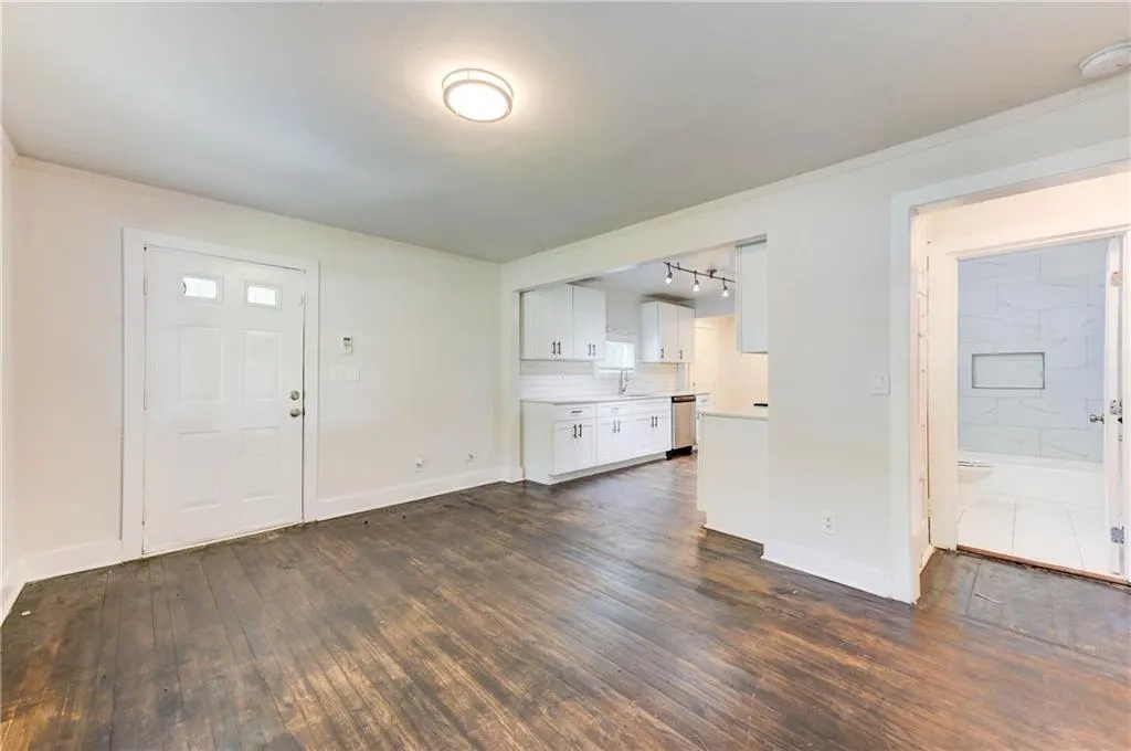 Foyer entrance with rail lighting, dark wood-style flooring, and ornamental molding